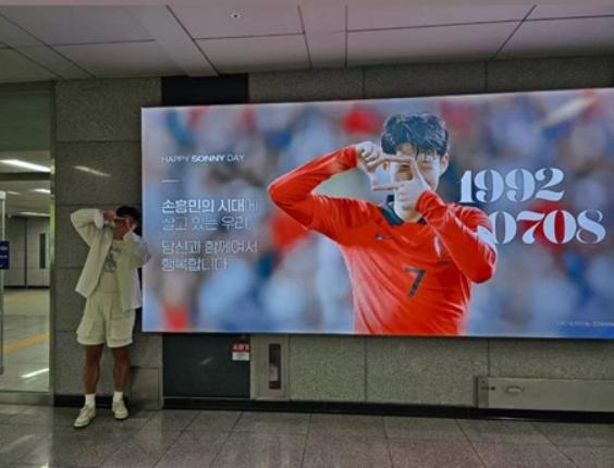 韩国足球队队长孙兴慜在球迷为自己庆生准备的广告牌前合影(1)
